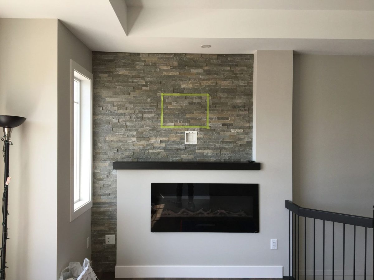 Stone feature wall with mounted TV and floating shelf