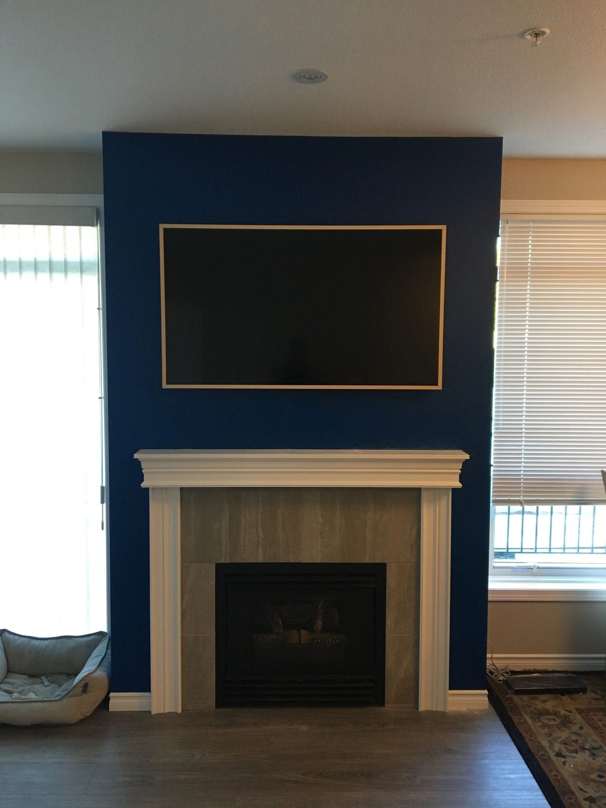 Framed TV mounted on a navy feature wall above a fireplace