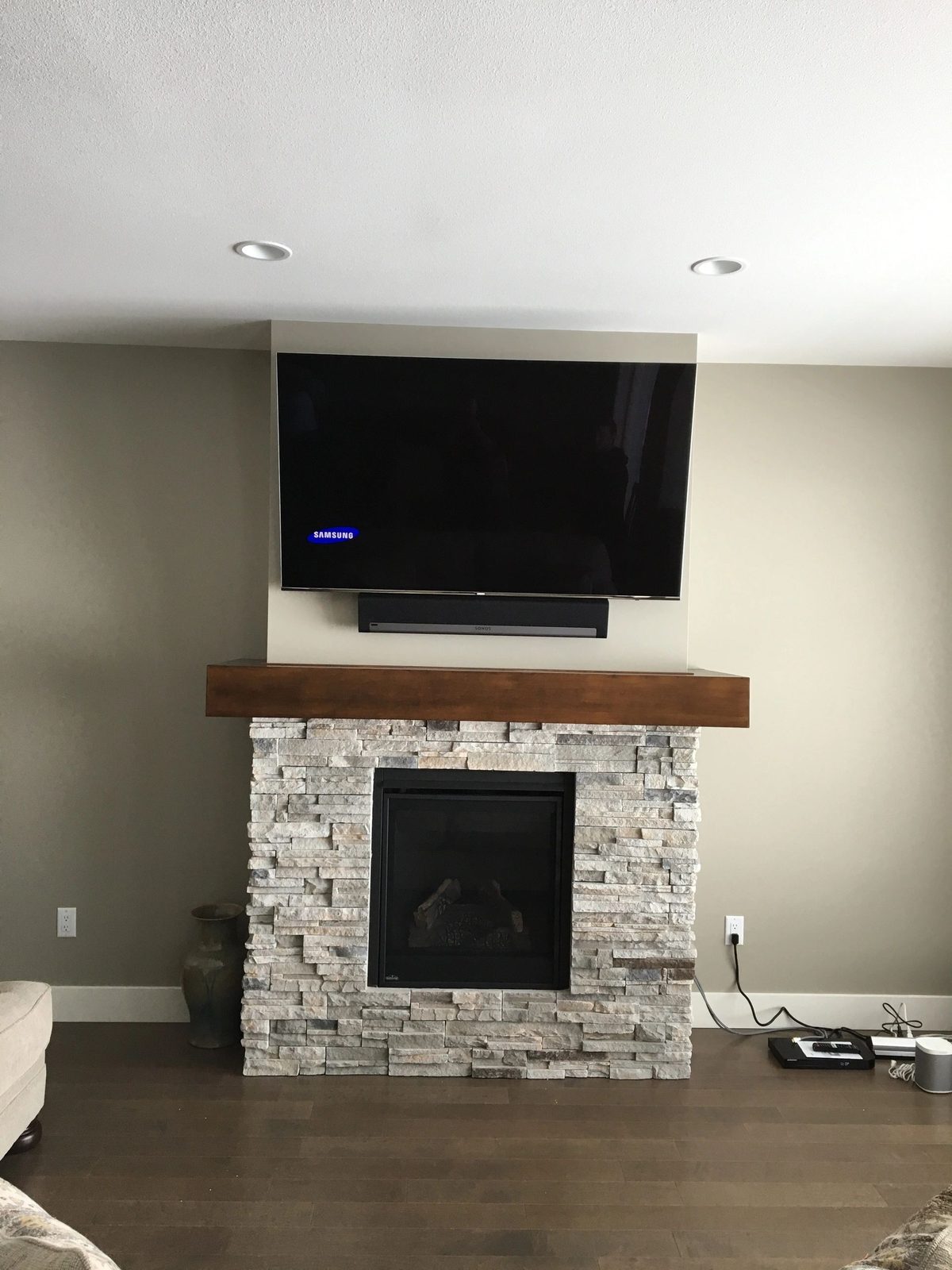 TV with soundbar mounted above a stacked stone hearth