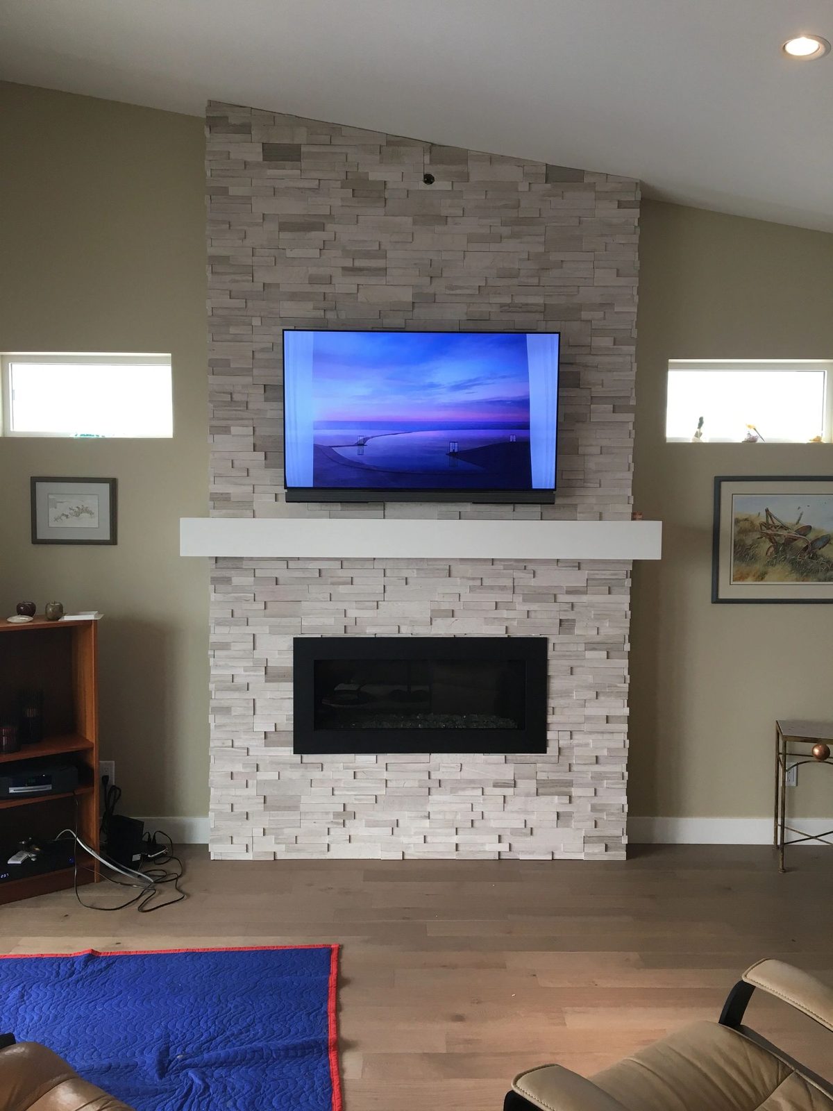 TV and soundbar mounted above a stone fireplace