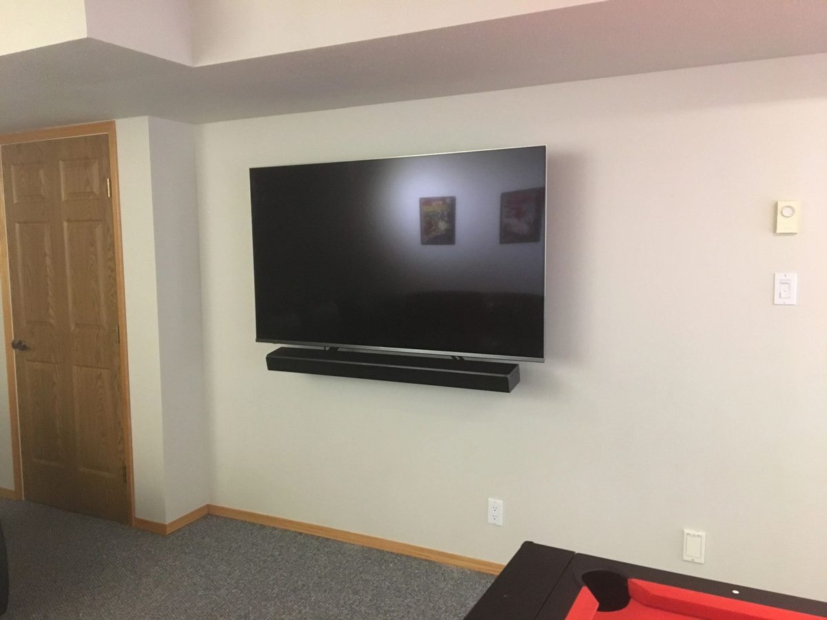 TV and soundbar mounted on a plain drywall feature wall