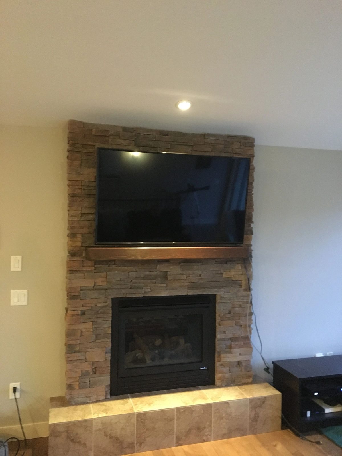 TV mounted above a fireplace on a stone feature wall