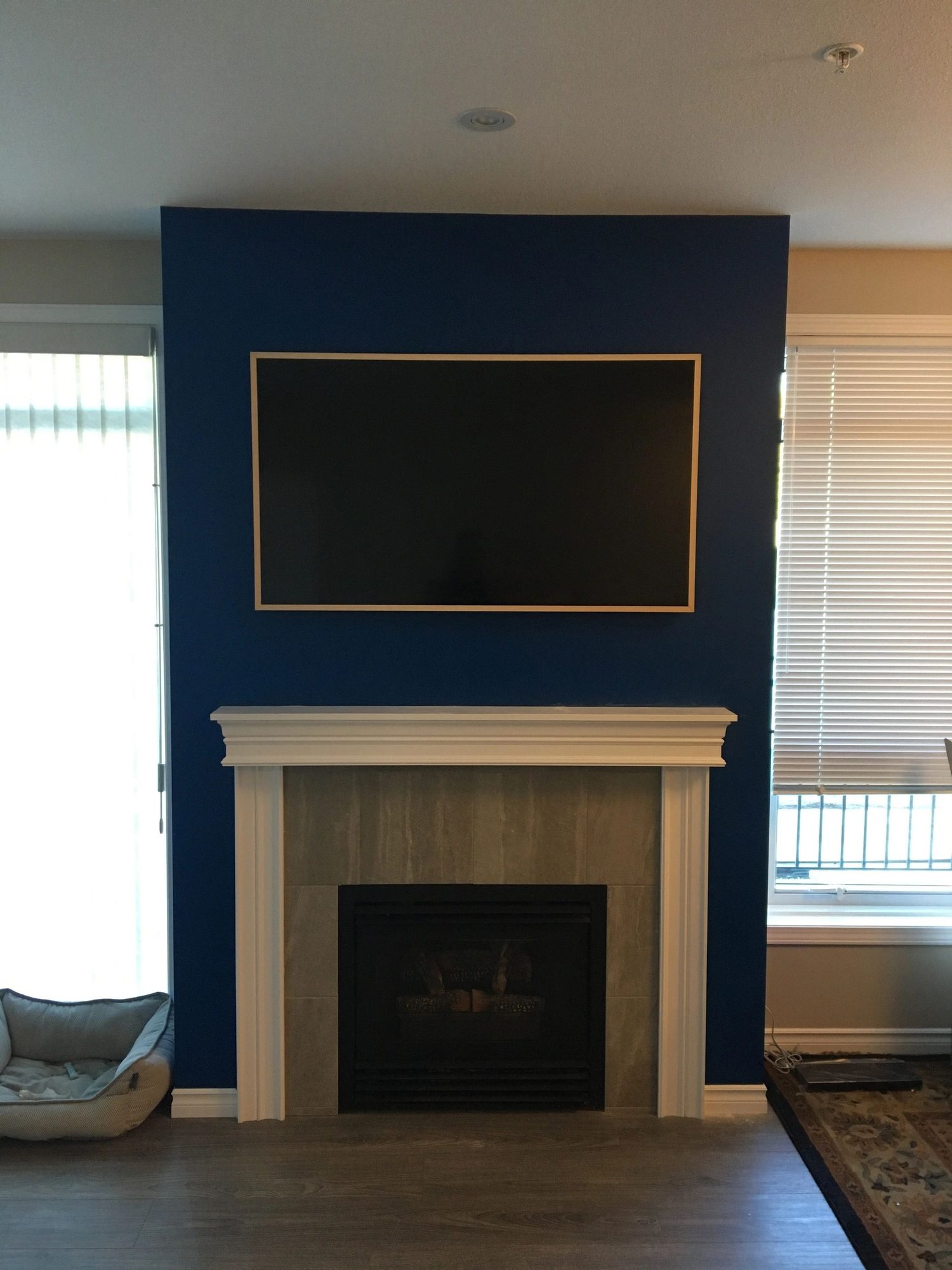 Framed TV mounted flush on the navy feature wall with no visible cables