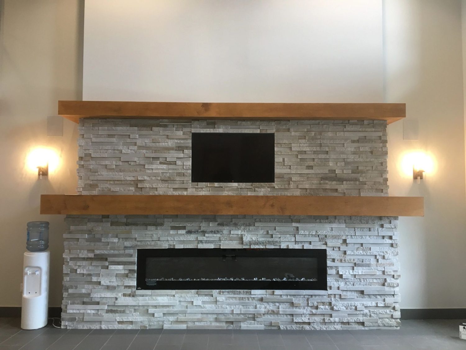 TV recessed into the stacked stone wall between the sconces