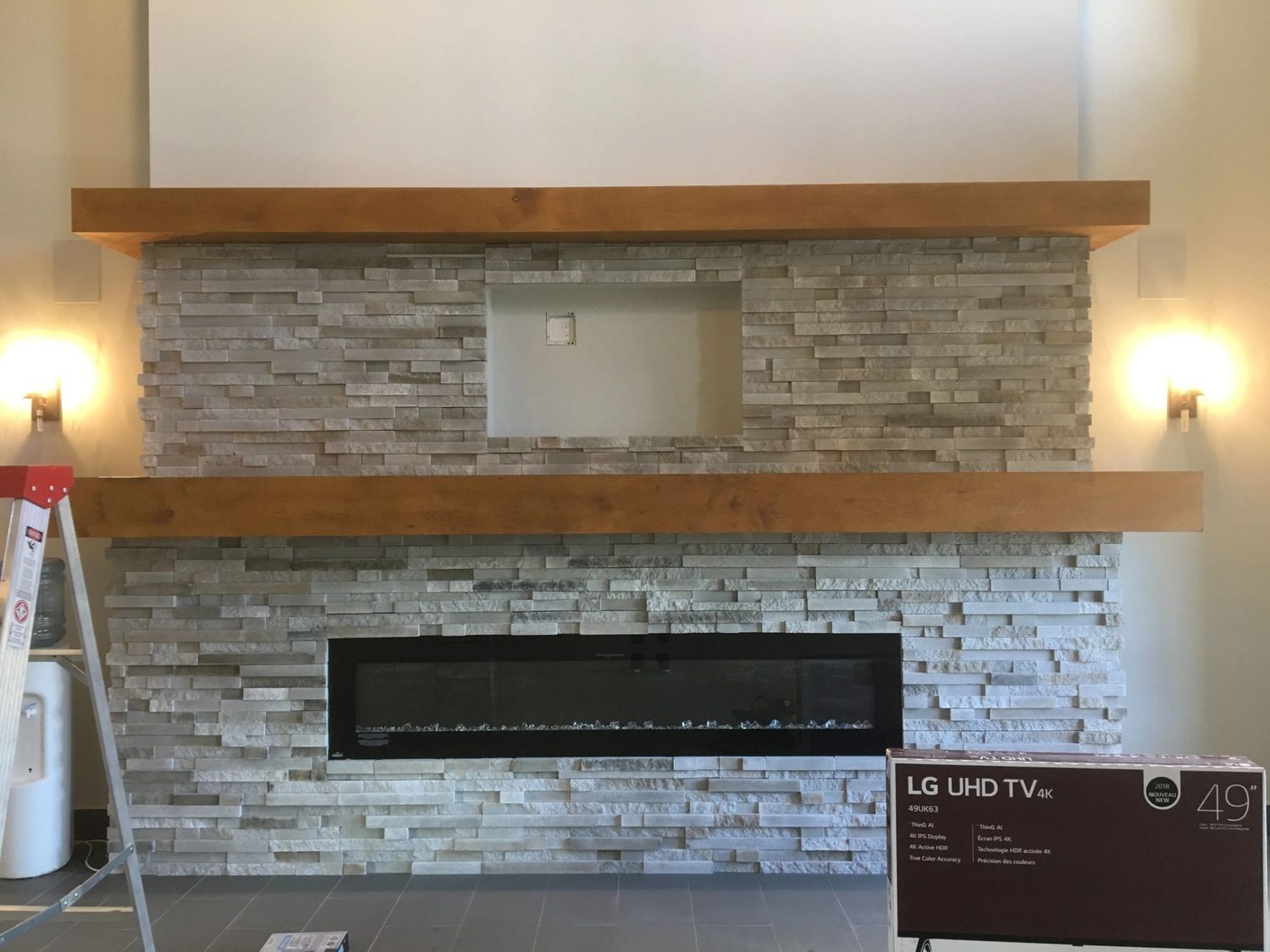 Empty stacked stone recess with timber mantle and wall sconces