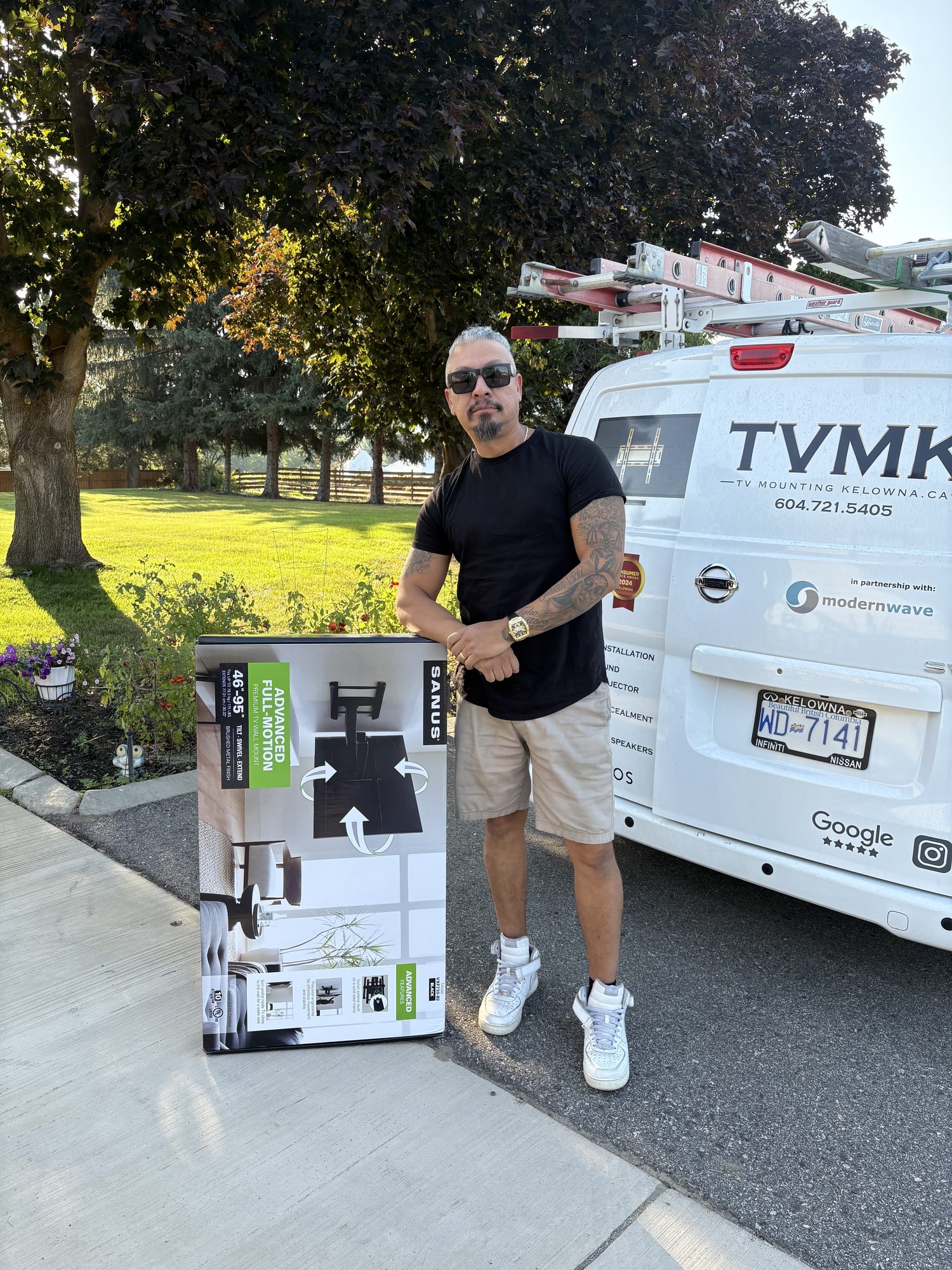 Wil Martinez beside the TV Mounting Kelowna van with a full-motion wall mount